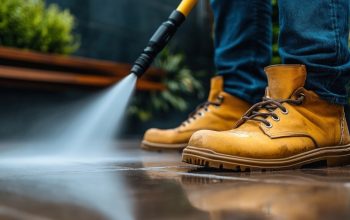 man pressure washing a concrete driveway